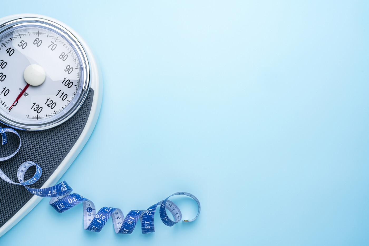 A scale and a measuring tape are pictured near the side of a blue background.