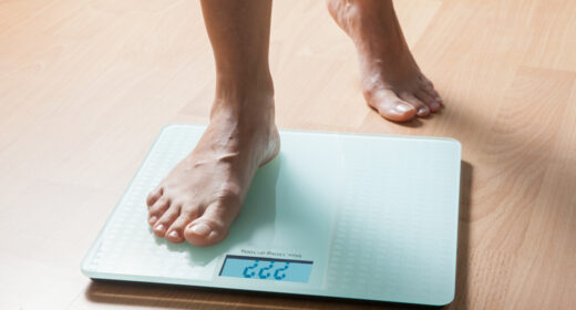 In a close-up image of a scale, a person is seen stepping on it, with one foot still on the floor.