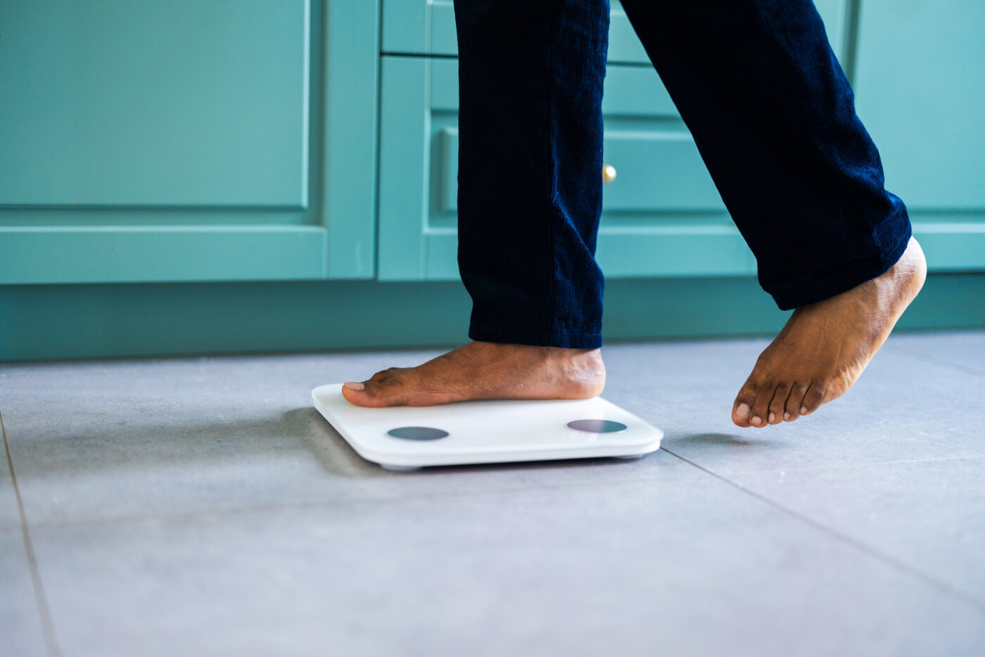 A photo shows the feet and lower legs of a person stepping on a scale.