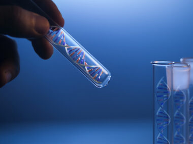 A hand holds a glass tube containing a DNA molecule next to several identical tubes.
