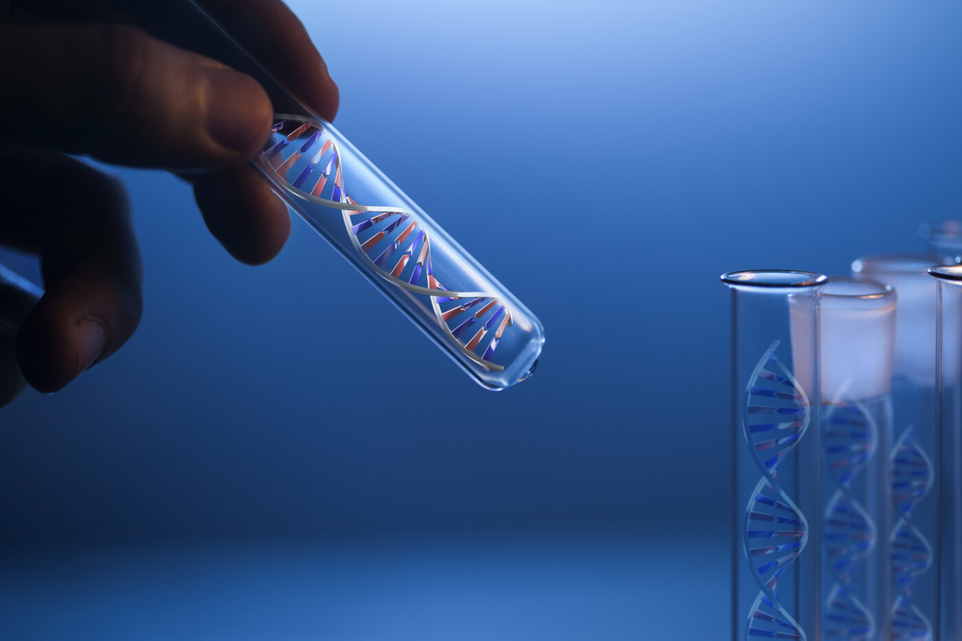 A hand holds a glass tube containing a DNA molecule next to several identical tubes.