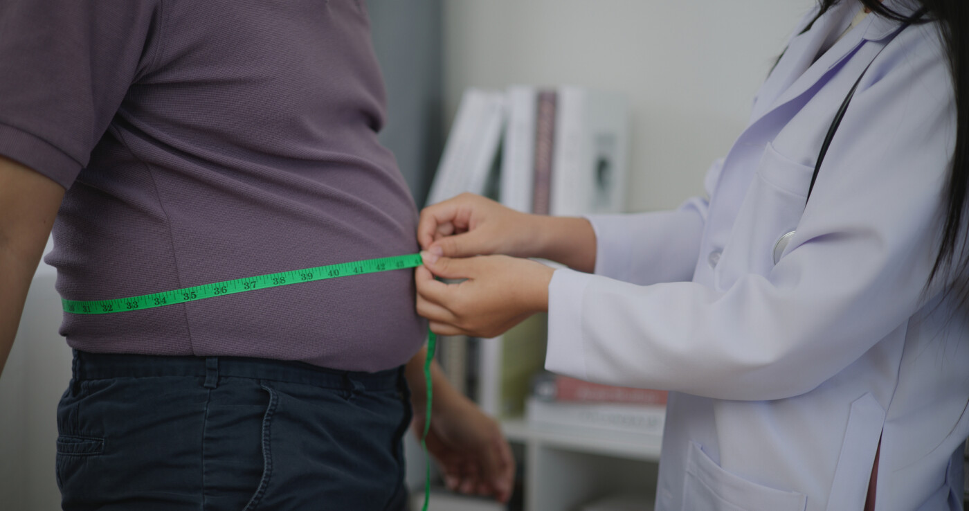 A medical professional uses measuring tape to measure a person's waist.