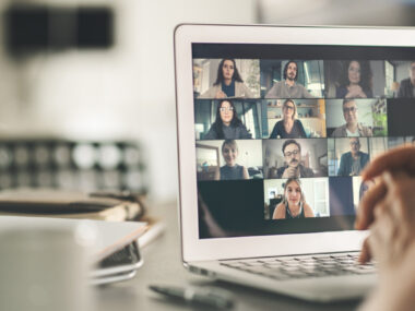A laptop screen shows people in an online meeting.