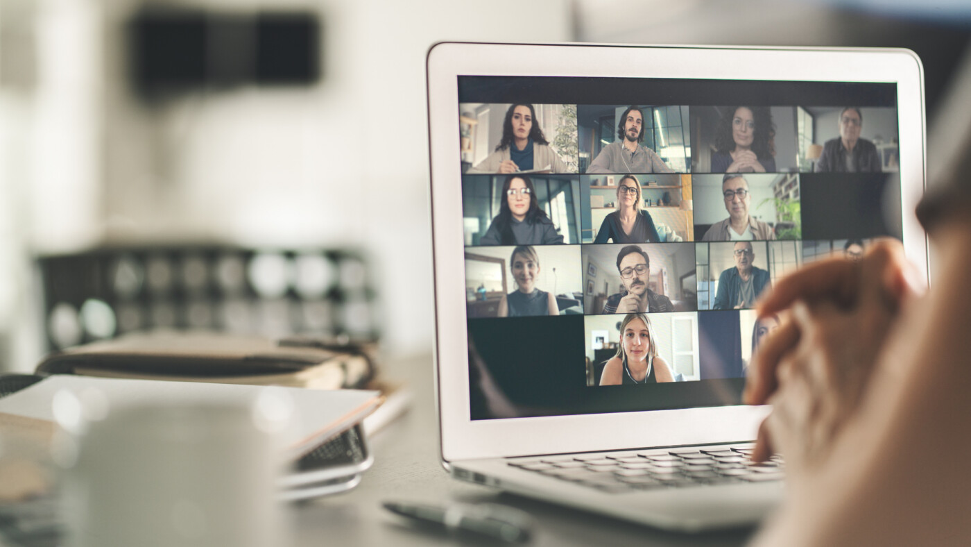 A laptop screen shows people in an online meeting.